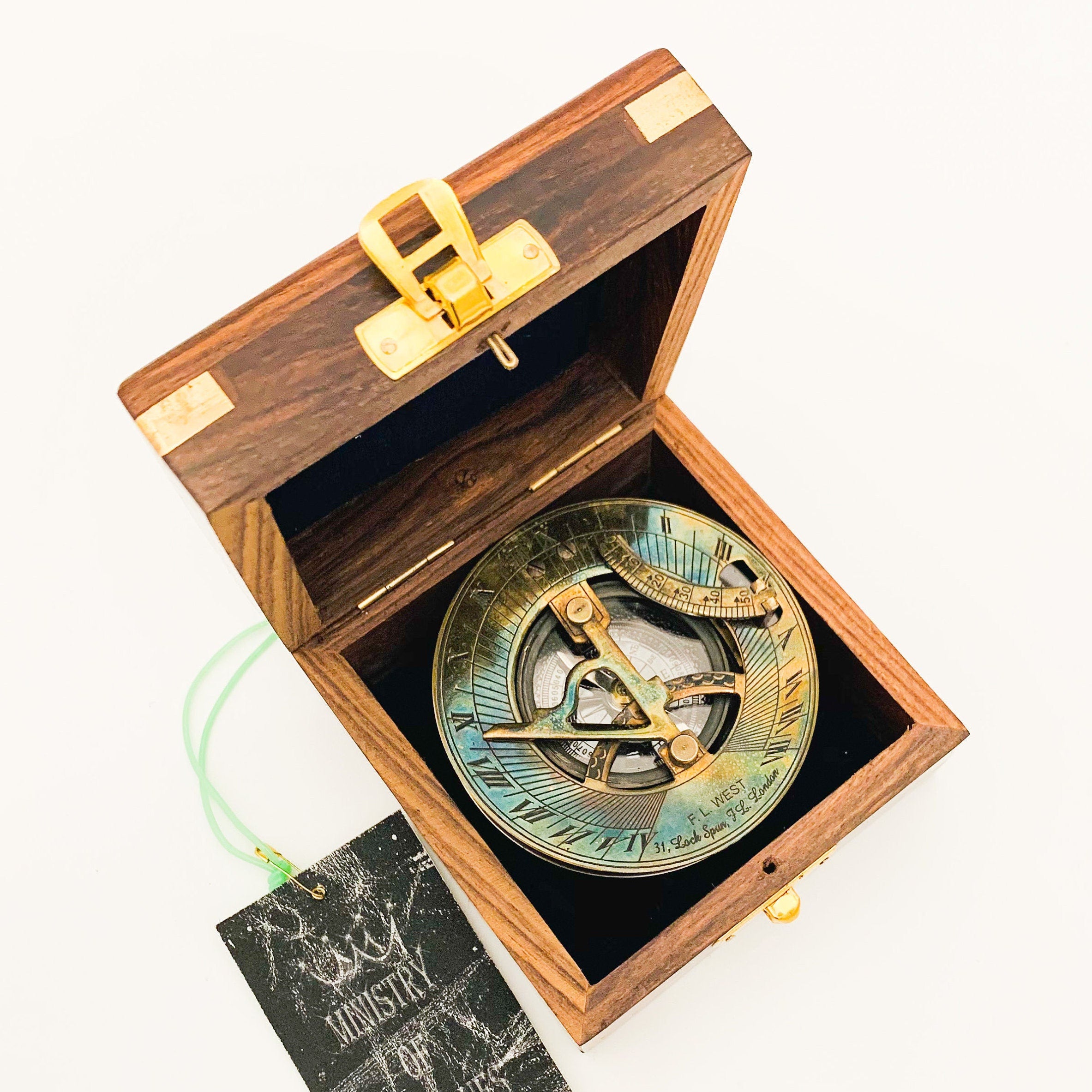 Peut inclure: Un compas de soleil en laiton dans une boîte en bois avec un loquet en laiton. Le compas a un cadran iridescent bleu et vert avec des chiffres romains et des marques. La boîte est en bois foncé avec une incrustation en bois clair.