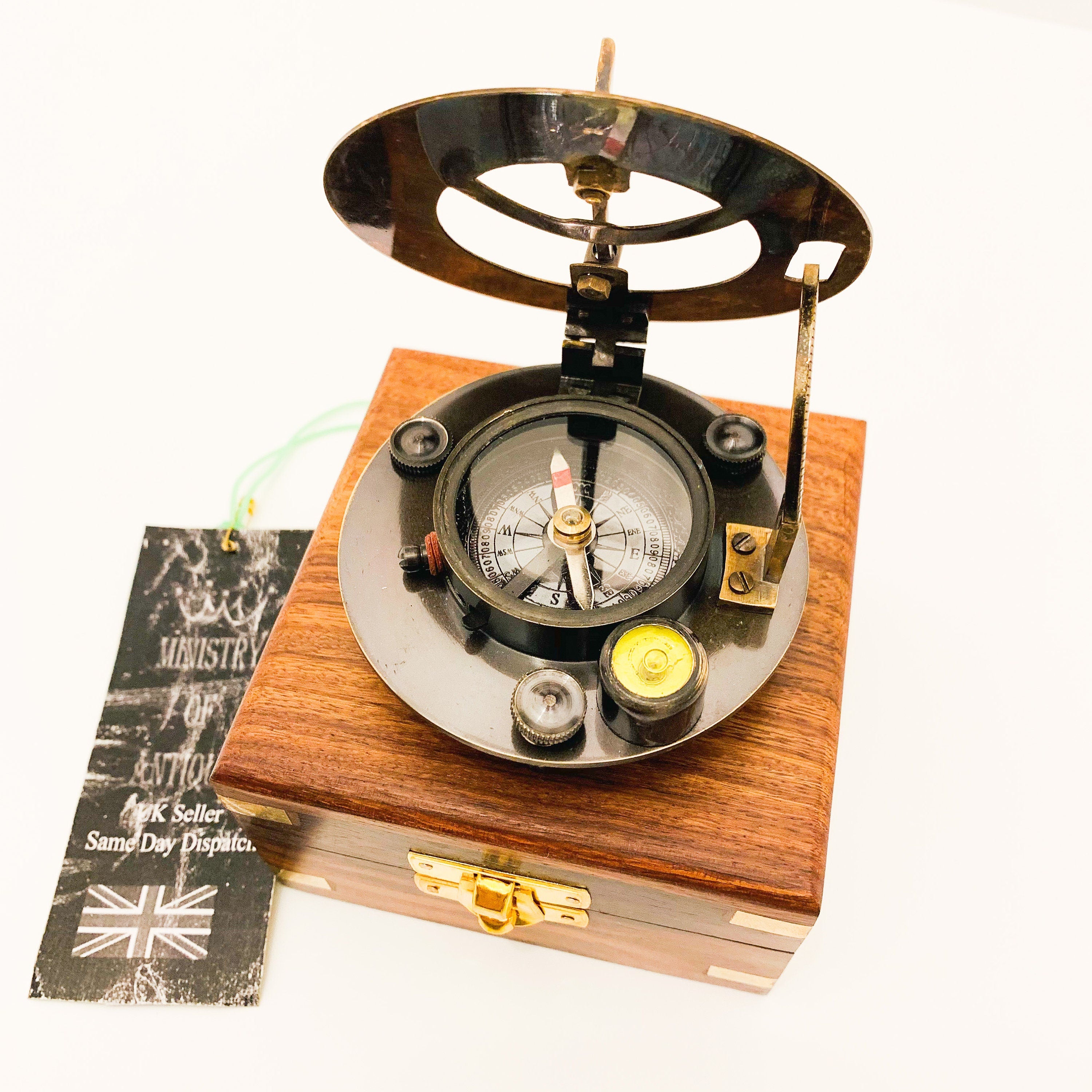 Peut inclure: Un compas et un cadran solaire en laiton dans une boîte en bois. Le compas a un cadran noir avec des marques blanches et une aiguille rouge. Le cadran solaire a un cadran en laiton avec un pointeur noir. La boîte est en bois foncé avec des accents en laiton.