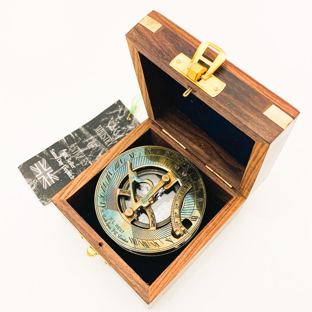 Peut inclure: Un compas de soleil en laiton dans une boîte en bois. Le compas a un cadran en laiton avec des chiffres romains et une rose des vents. La boîte est en bois foncé avec des accents en laiton.