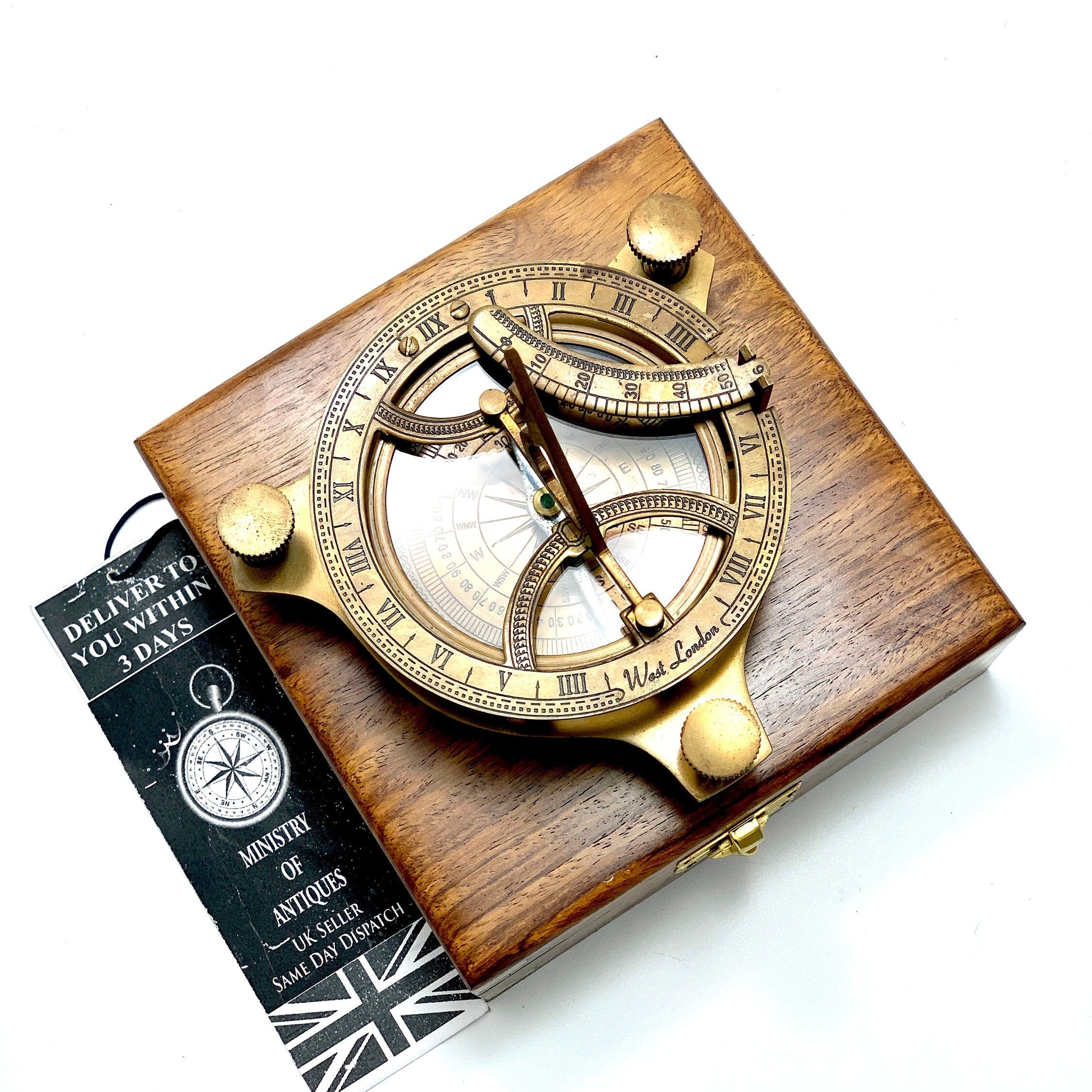 May include: A brass sundial with a compass and a wooden box. The sundial features Roman numerals and a compass rose. The box is made of dark wood and has a brass latch.