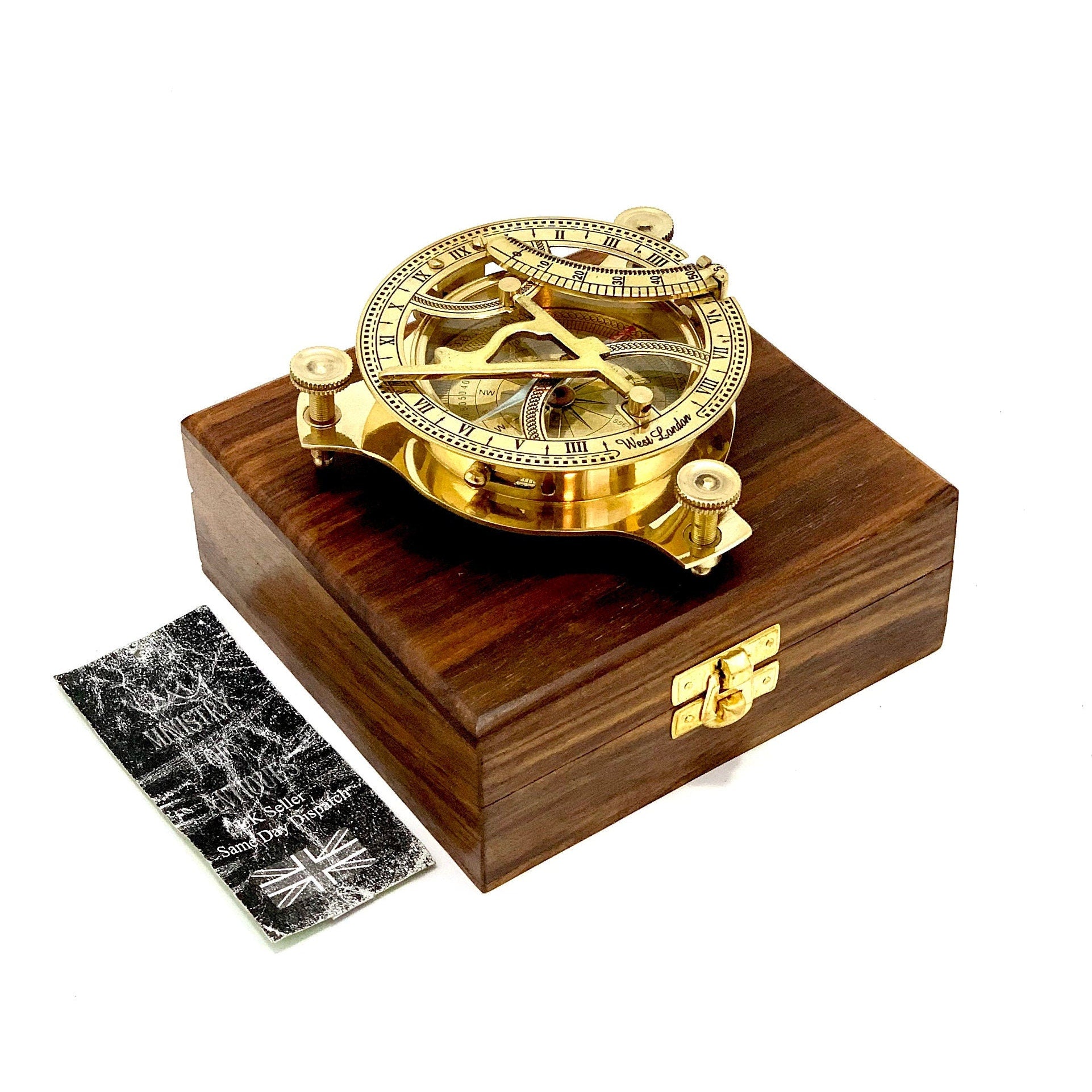 May include: A brass sundial with a compass and a wooden box. The sundial has Roman numerals and a West London inscription.