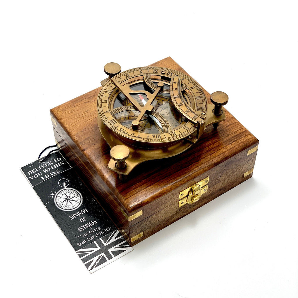 May include: A brass compass with a wooden box. The compass features a sundial and a compass rose. The box is made of dark wood with brass accents.