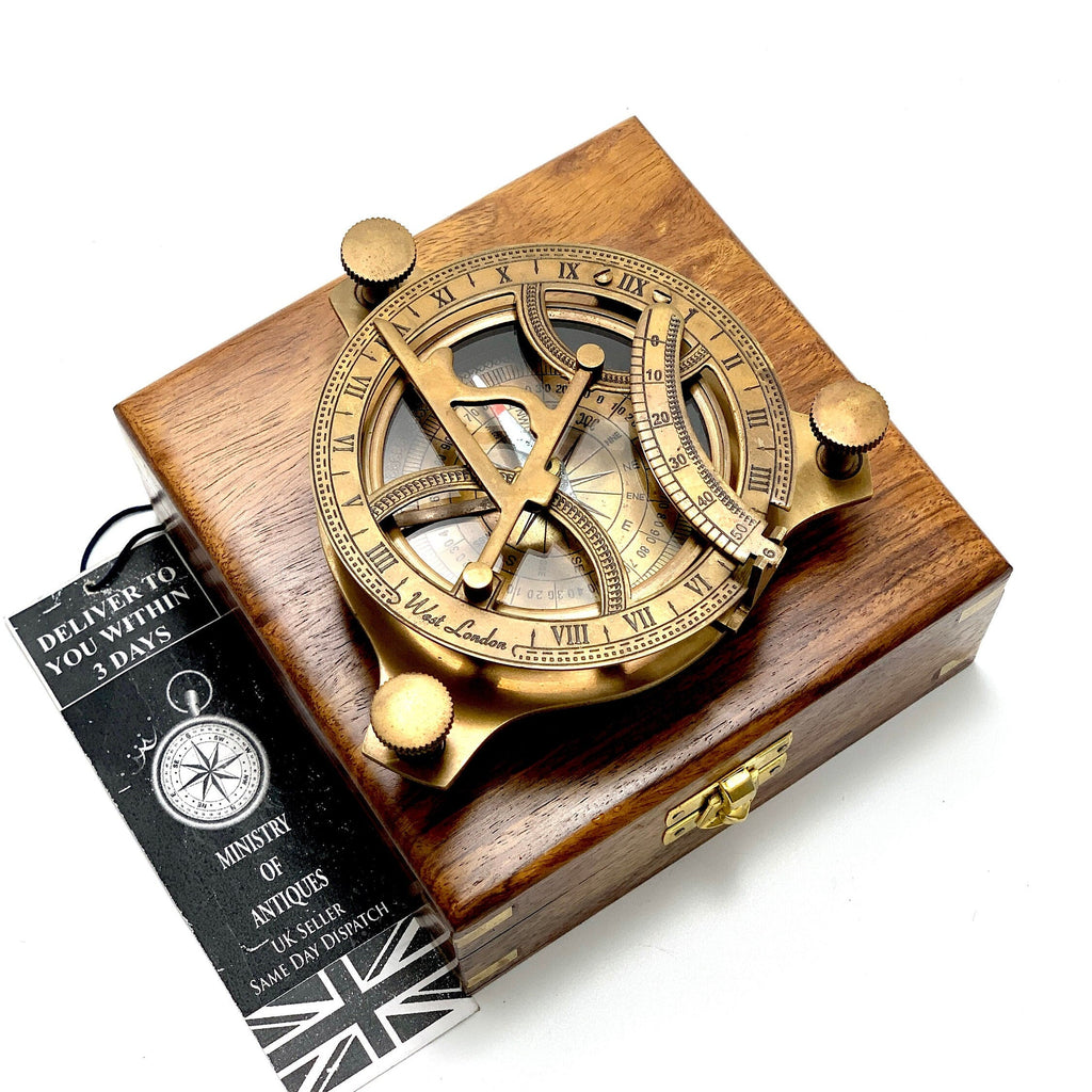 May include: A brass compass with a wooden box. The compass has a compass rose, a sundial, and a time scale. The compass is labelled "West London".