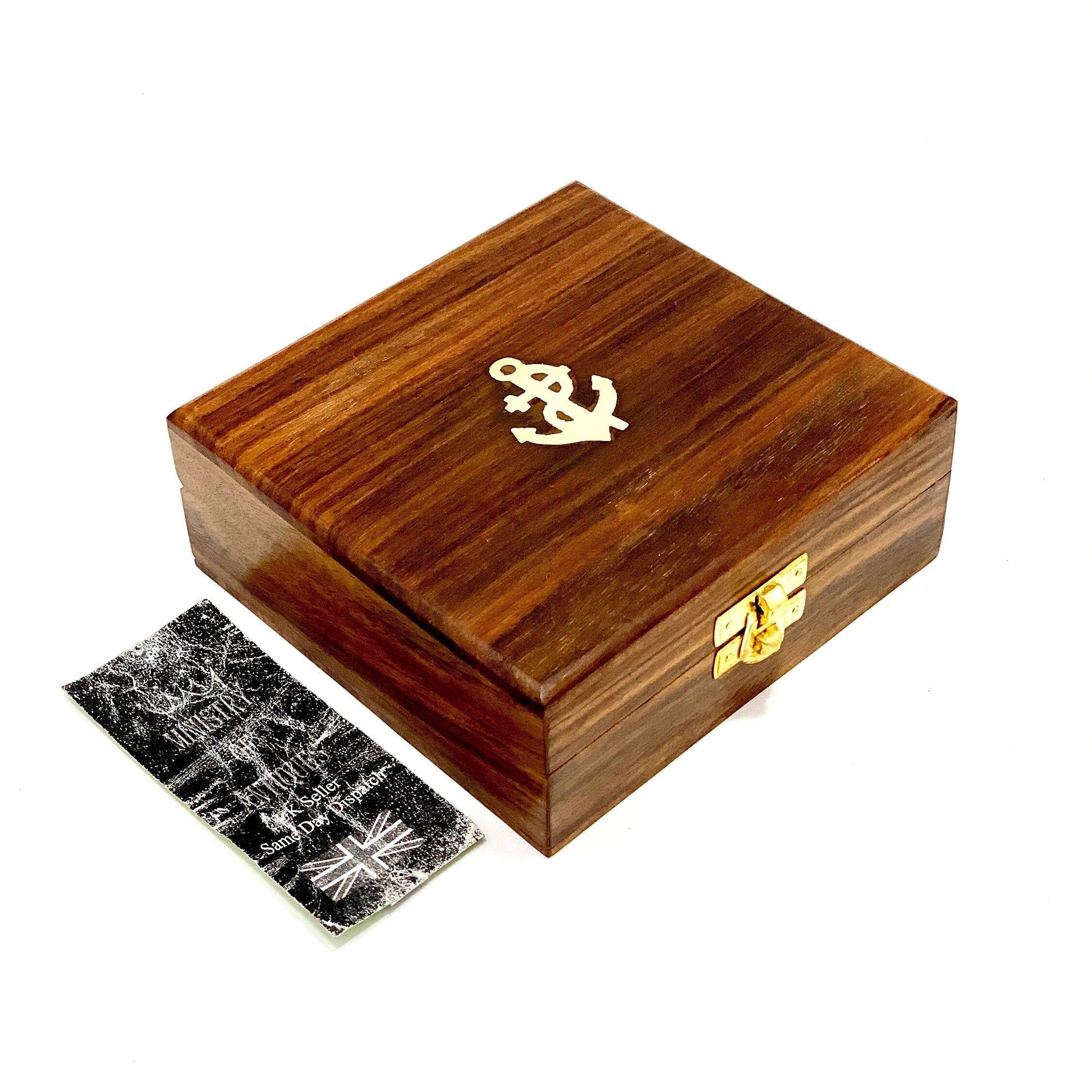 May include: A wooden box with a brass anchor design on the lid. The box has a brass latch and is made of dark wood.