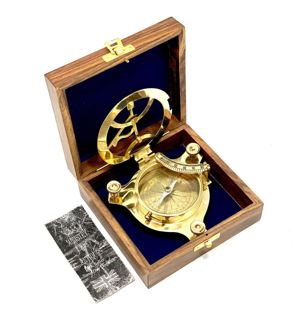 May include: A brass compass and sundial in a wooden box with a blue velvet lining. The compass has a white needle and a green arrow. The sundial has a brass frame and a clear glass lens. The box has a brass latch and a brass hinge.