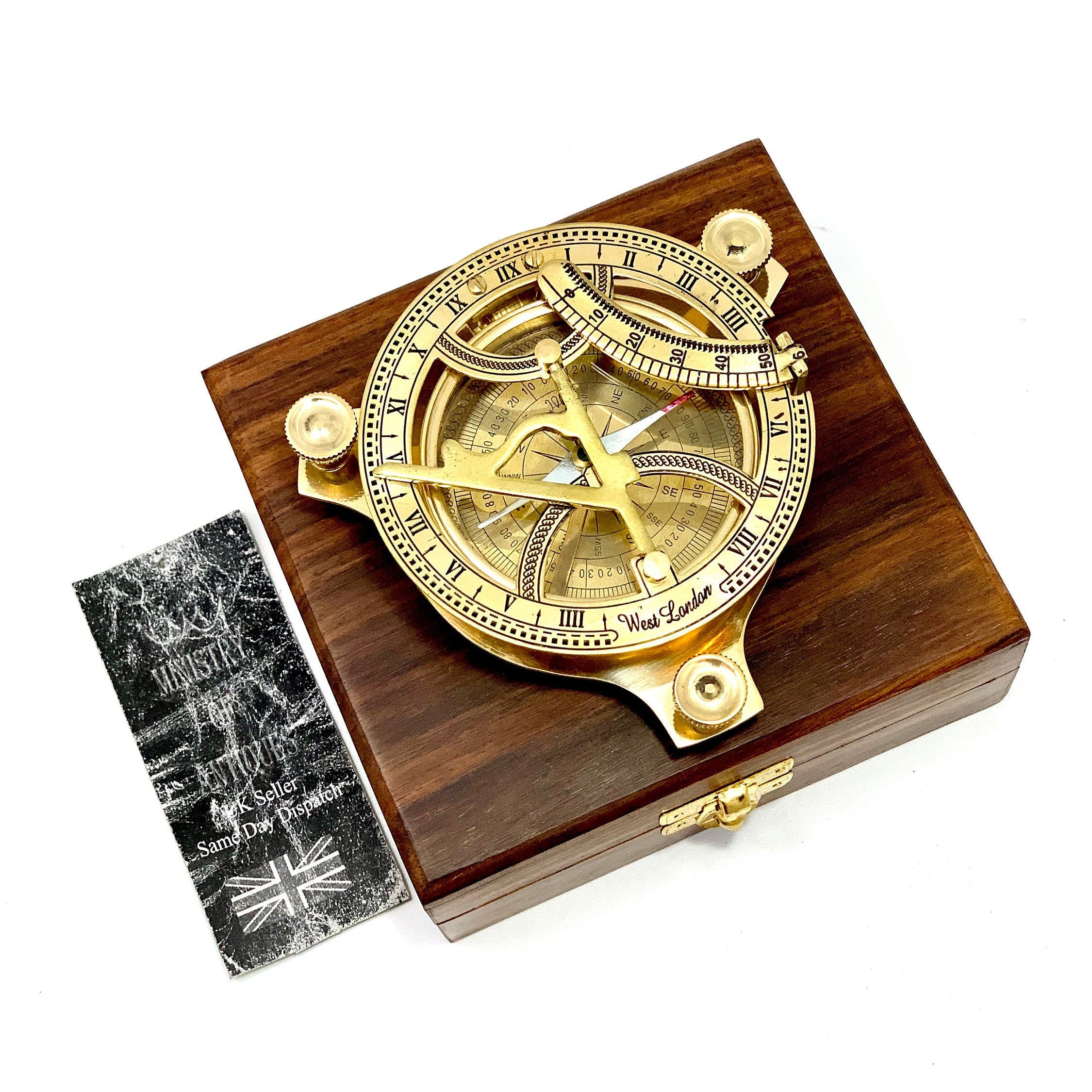 May include: A brass compass with a wooden box. The compass features a compass rose, a sundial, and a protractor. The box is made of dark wood and has a brass latch.