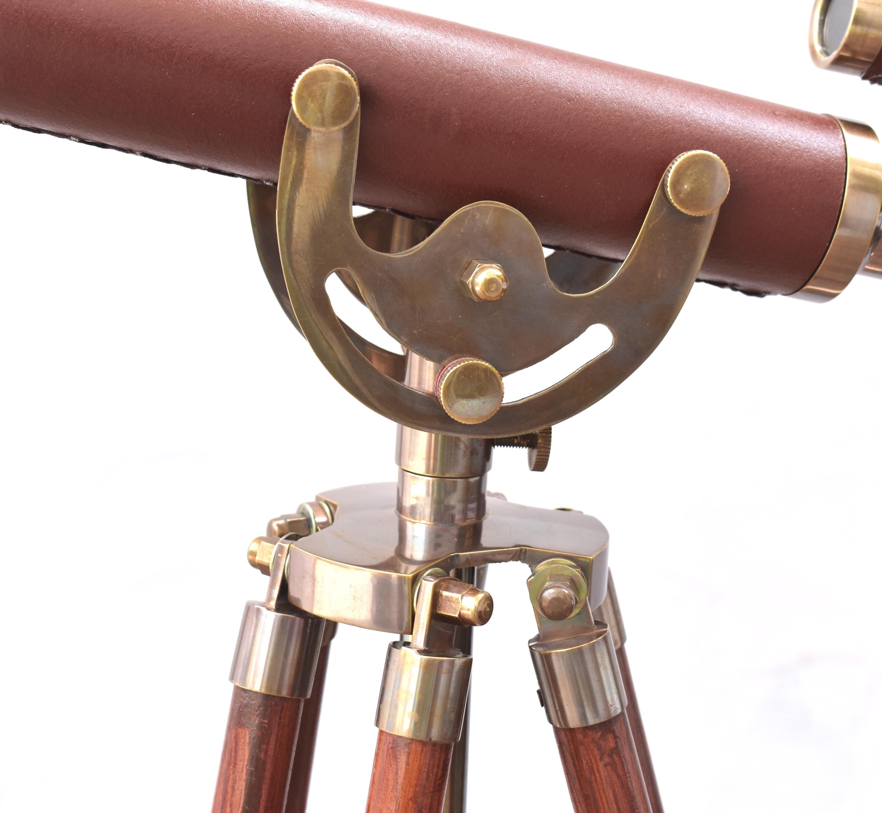 May include: A vintage telescope featuring a brown leather-covered barrel and brass fittings. It is mounted on a wooden tripod with brass detailing, evoking a classic nautical design. The telescope's height is adjustable.