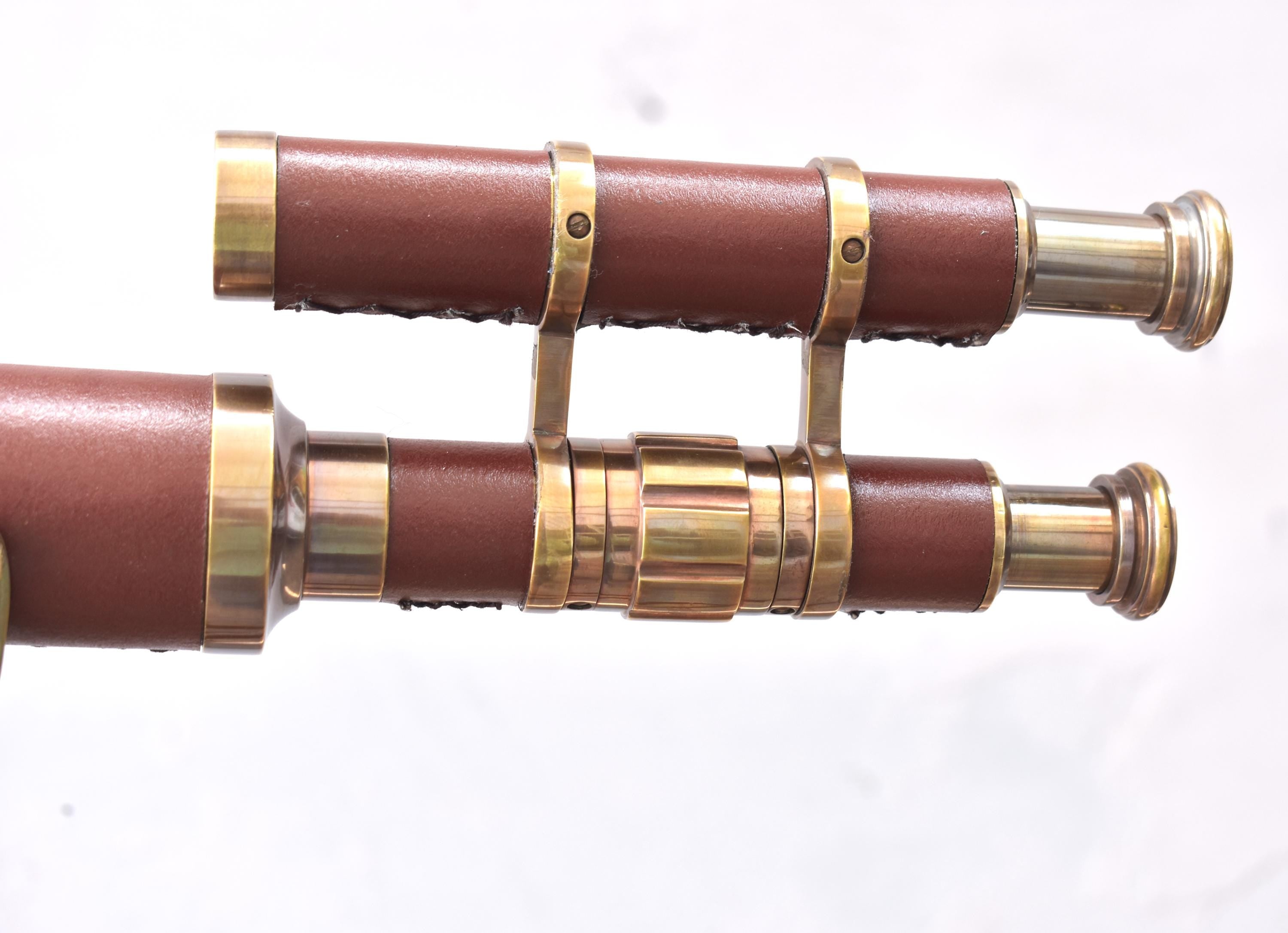 May include: Two antique-style telescopes with brown leather-wrapped barrels and brass accents. The telescopes are connected by a brass support. The design evokes a vintage nautical theme.