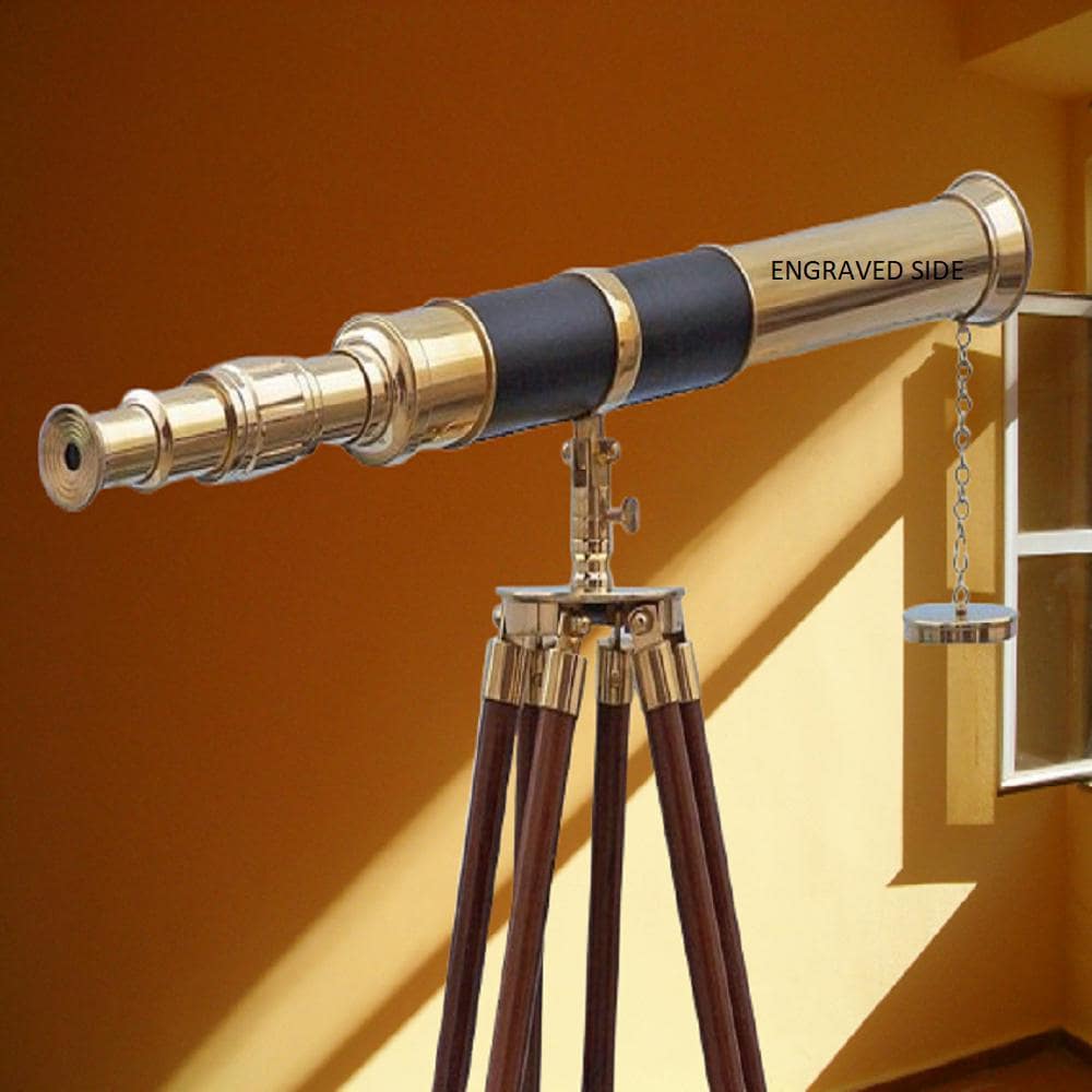 May include: A brass and black telescope with the words "ENGRAVED SIDE" on the side. The telescope is mounted on a wooden tripod. The telescope is a vintage nautical instrument.