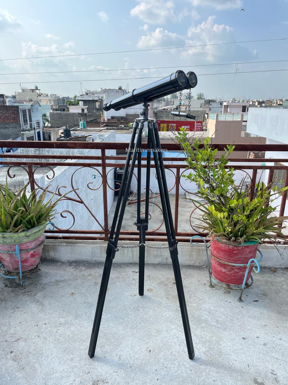 Può includere: Un telescopio nero montato su un treppiede nero, ideale per l'osservazione a distanza. Il treppiede ha gambe regolabili per la stabilità. Lo sfondo presenta edifici e un cielo nuvoloso. Il telescopio ha due oculari.