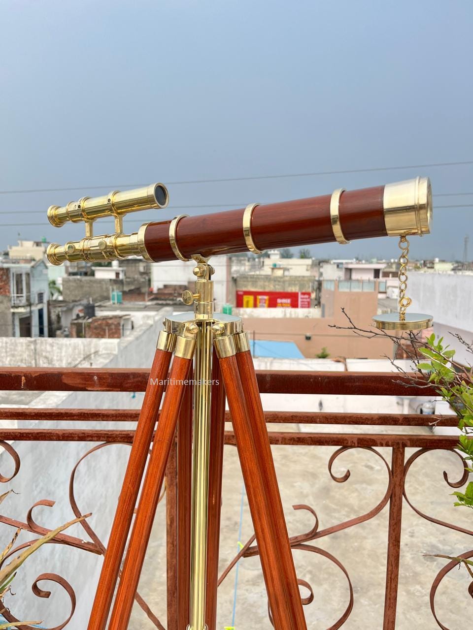 May include: A classic telescope featuring a dark brown wooden barrel and brass detailing. It is mounted on a wooden tripod with brass fixtures. The design suggests a nautical or scientific aesthetic.