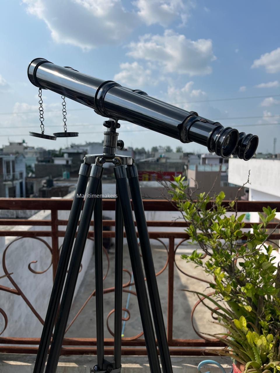 Può includere: Un telescopio nero con finitura argentata, montato su un treppiede nero. Il telescopio ha una canna lunga e più lenti. Il treppiede ha tre gambe. L'immagine è scattata all'aperto con un cielo blu sullo sfondo.