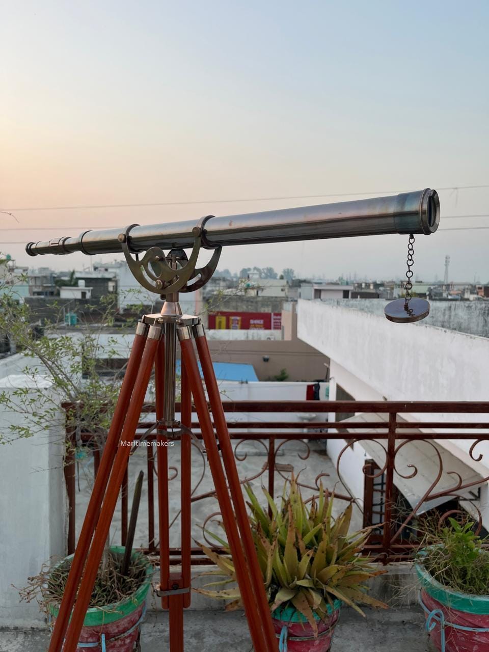 Può includere: Un telescopio in stile vintage con un tubo in metallo lucido e dettagliati raccordi in ottone. È montato su un treppiede in legno con finitura marrone scuro. Il telescopio è progettato per l'osservazione.