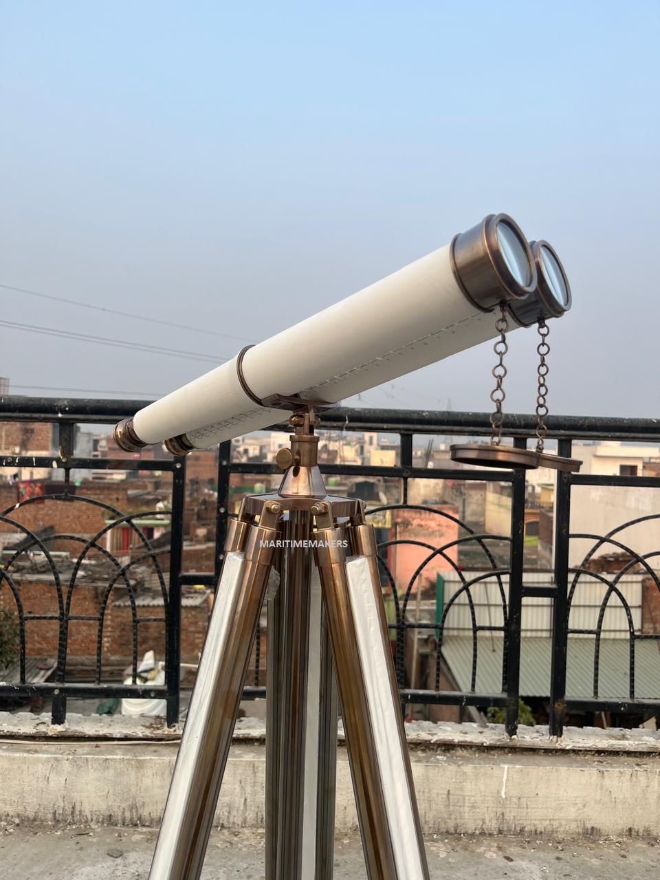 May include: A white and brass nautical telescope on a tripod. The telescope features a white barrel with brass detailing and lenses. The tripod has a brass finish with white accents. The text "MARITIMEMAKERS" is visible on the tripod.